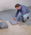 Contractors installing basement subfloor tiles and matting on a concrete basement floor in Framingham, Massachusetts and Rhode Island